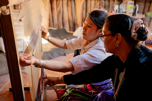 A Grandmother keeping the Navajo tradition alive for the younger generation by teaching granddaughter how to weave