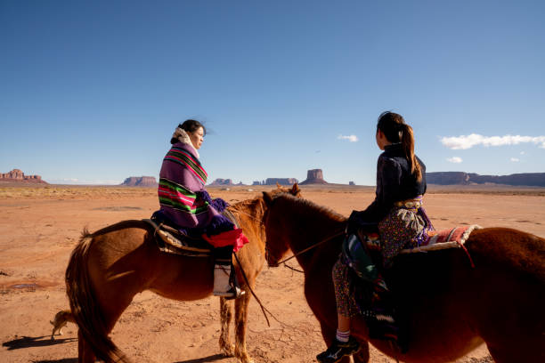 istock Young Navajo Siblings On Their Horses With A Rock Formation Behind Them 1210458648