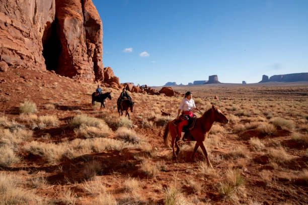 junge navajo-geschwister reiten ihre pferde auf dem land ihrer familie im monument valley - monument valley navajo mesa monument valley tribal park stock-fotos und bilder