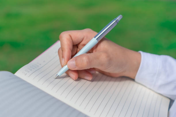 istock Woman hand writing down in small white memo notebook for take a note not to forget or to do list plan for future. 1210459738