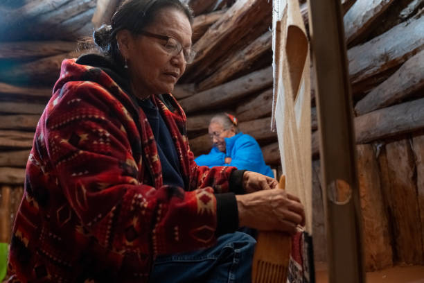 una donna navajo tesse una coperta da sella su un telaio, sua madre sullo sfondo - land craft foto e immagini stock