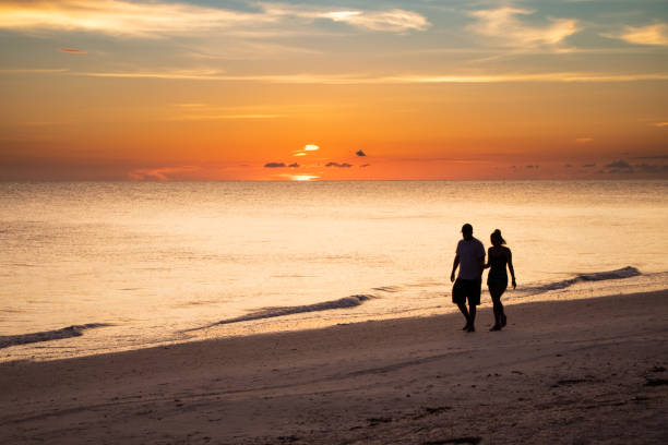 istock Couple strolls along a Florida beach at sunset 1210460642