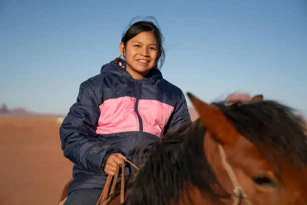 A closeup of a teenage Navajo girl on a horse