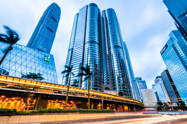 Modern business buildings with blue sky in hong kong Hong Kong - July 30, 2019: Street traffic in Hong Kong at night. Office skyscraper buildings and busy traffic on highway road with blurred car light trails. Hong Kong. standard chartered bank stock pictures, royalty-free photos & images