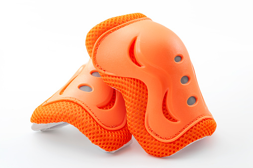 Cycling safety equipment, extreme sports and bicycle riding gear conceptual idea with orange knee pads isolated on white background with clipping path cutout