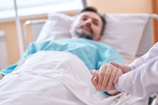 Supporting patient before surgical operation Close-up of unrecognizable doctor holding hand of patient while supporting him before surgical operation hospital depression sadness bed stock pictures, royalty-free photos & images