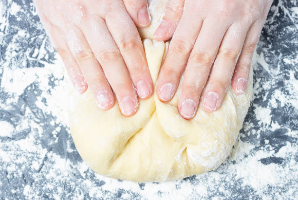 istock Female hands mix dough close up top view gray background. 1210482213