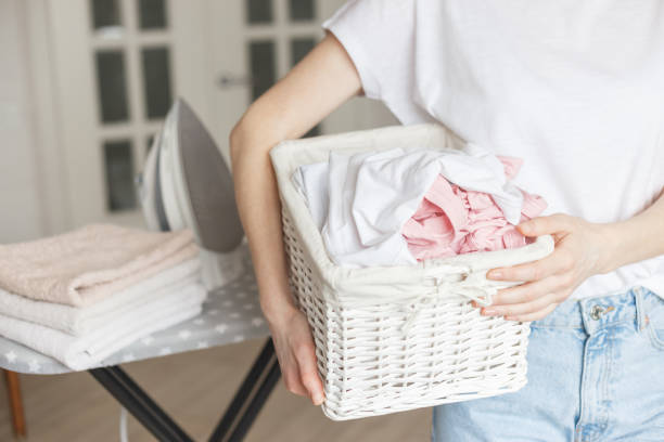 istock Wicker rustic basket with washed clothes in woman's hand ready to ironing 1210484183