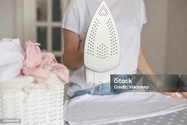 Woman Holds Modern Styled Iron With Nonstick Cover While Ironing Stock Photo - Download Image Now