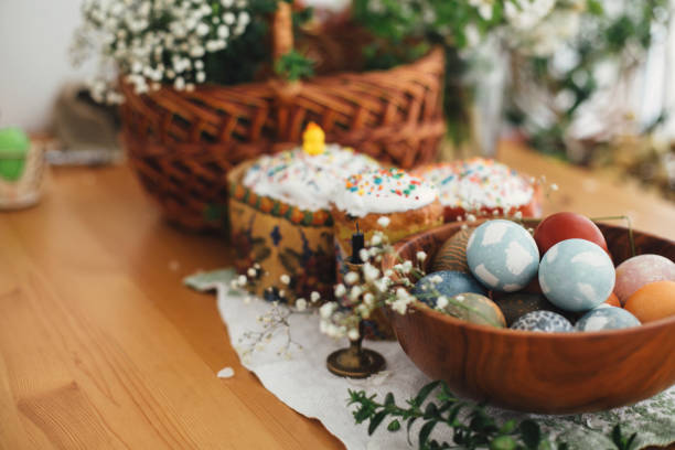 Stylish easter eggs natural dyed on background of homemade easter cake, candle, green branches and flowers with wicker basket on wooden rustic table. Easter Food for sanctify Stylish easter eggs natural dyed on background of homemade easter cake, candle, green branches and flowers with wicker basket on wooden rustic table. Easter Food for sanctify orthodox church photos stock pictures, royalty-free photos & images