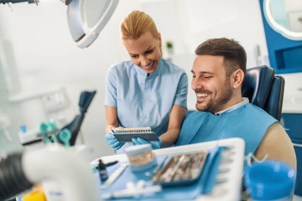 Doctor makes comparison of the patient teeth with the dental whitening chart stock photo