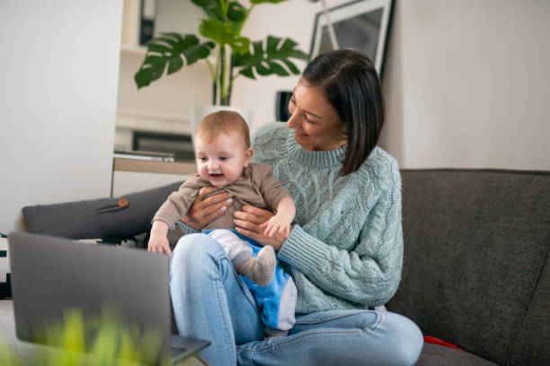 Businesswoman with baby boy working from home stock photo