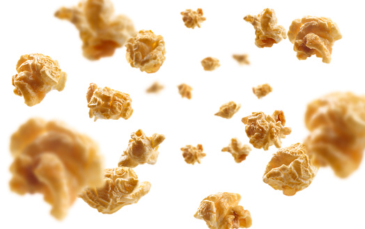 Caramel-flavored popcorn levitates on a white background.