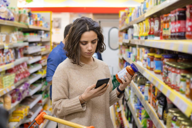 istock Focused woman using smartphone in grocery store 1210492672