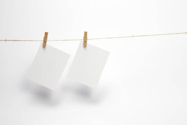 istock Empty paper frames that hang on a rope with clothespins and isolated on white. 1210494054
