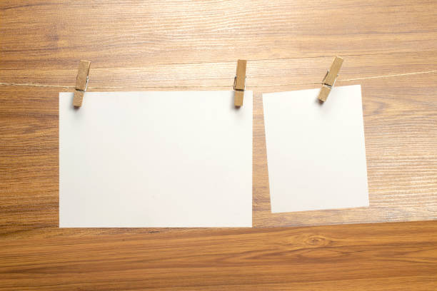 istock Empty blank paper frames that hang on a rope with clothespins and on wooden background. 1210496407