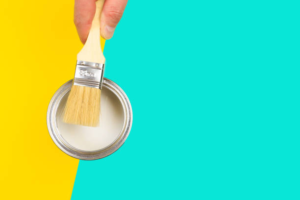 istock hand holding Brush  on open can of  paint on pastel multicolor  background. Renovation concept 1210496452