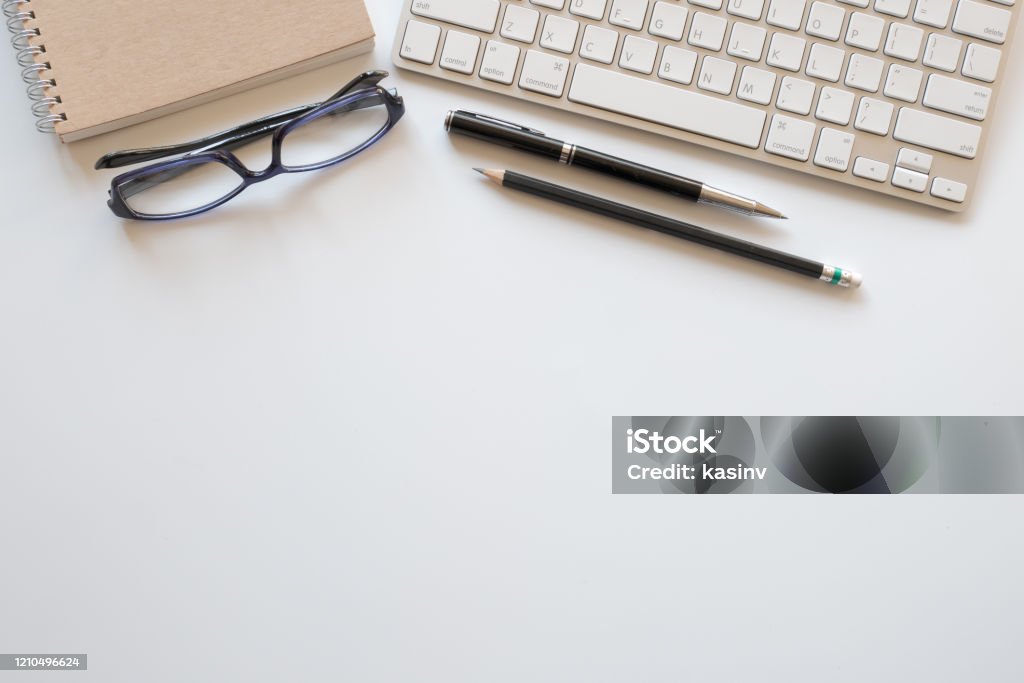 top view of workspace with computer keyboard and office supplies on white desk with copy space top view of modern workspace with computer keyboard and office supplies on white desk with copy space Desk Stock Photo