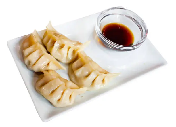 Japanese style boiled gyoza dumplings stuffed with minced pork served with soy tare sauce. Isolated over white background