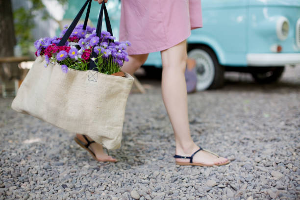 Woman with eco bag from sackcloth with pink and purple flowers Woman with eco bag from sackcloth with pink and purple flowers in a park flower market stock pictures, royalty-free photos & images