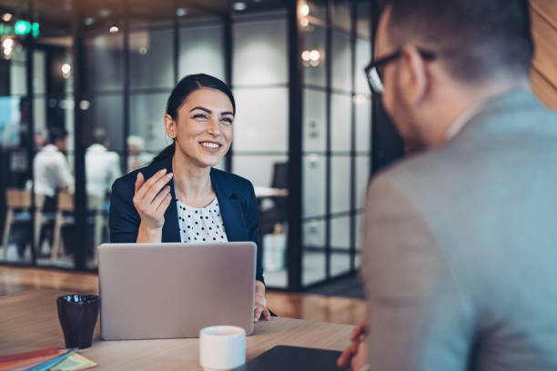 glimlachende onderneemster die aan een collega spreekt - interview evenement stockfoto's en -beelden