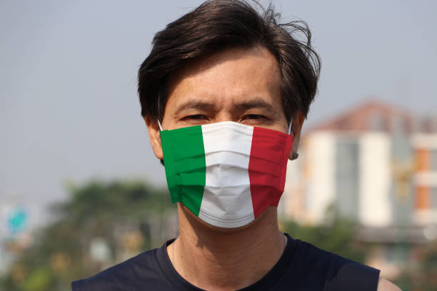 Italy flag on hygienic mask. Masked Asian man prevent germs. concept of Tiny Particle protection or virus corona. stock photo