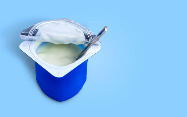 istock Yogurt, plastic cups and spoon on blue background. Yogurt made from milk fermented by added bacteria, often sweetened and flavored. 1210510597