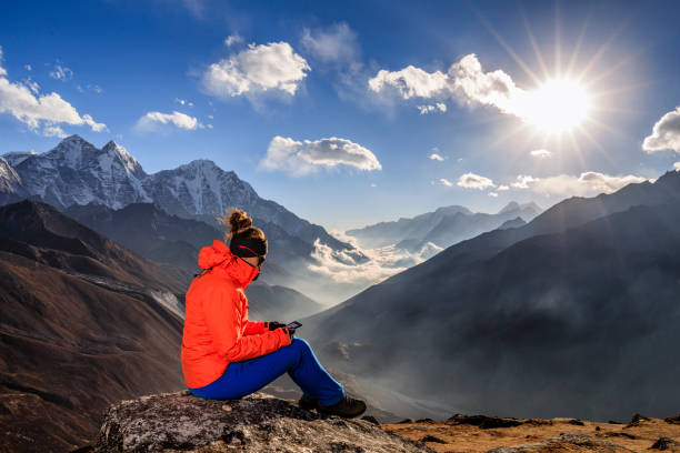 istock Woman reading a book on e-reader during sunset over Himalayas, Everest Region 1210510758