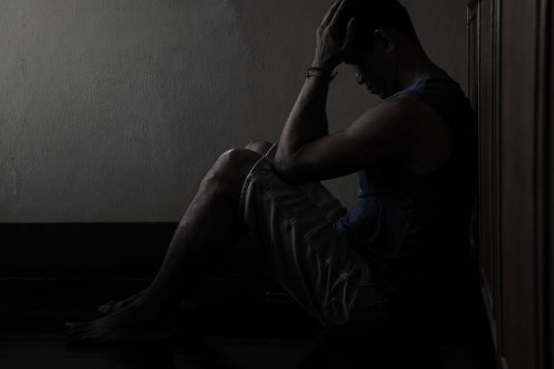 istock Desperate hopeless man with hands holding head sitting in dark corner 1210511104