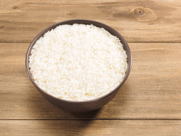 istock Long grain Basmati rice in brown ceramic bowl on brown wooden background 1210512136