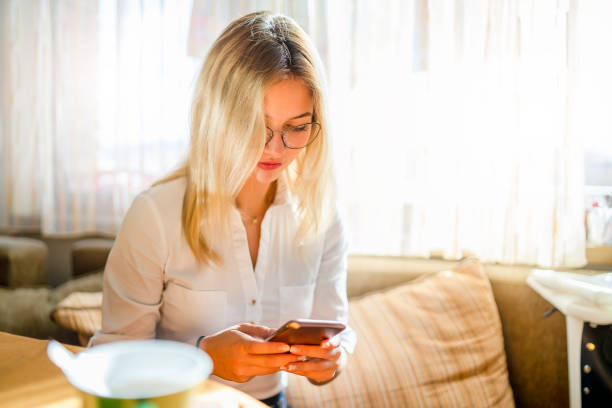 istock Young woman sitting  and uses mobile phone 1210513871