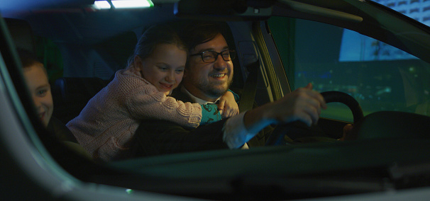 Medium shot of happy family traveling by car at night