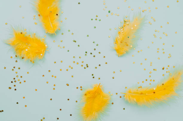 istock Abstract Easter holiday blue background with bright yellow feathers and gold shiny stars. 1210517408