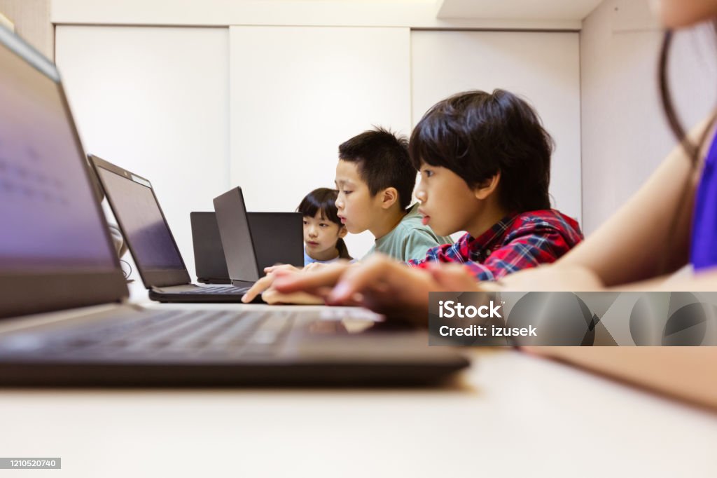 Students using laptop while coding in school Male and female students using laptop while coding at desk in class. Boys and girls are learning programming in school. They are studying on technologies. Child Stock Photo Students using laptop while coding in school Male and female students using laptop while coding at desk in class. Boys and girls are learning programming in school. They are studying on technologies. Child Stock Photo