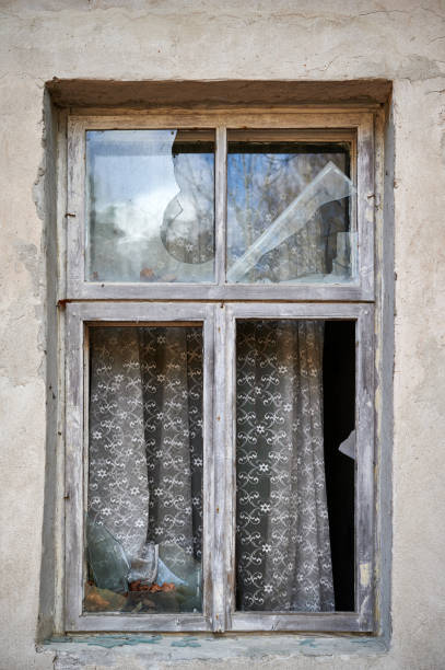 istock Broken window in old wall of abandoned house 1210522039