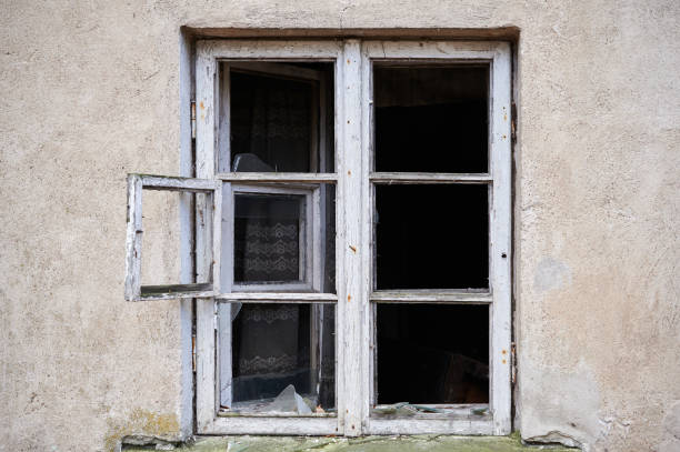 istock Broken window in old wall of abandoned house 1210522081