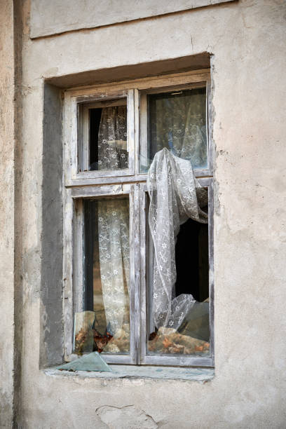 istock Broken window in old wall of abandoned house 1210522083