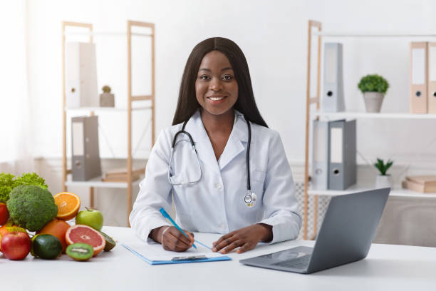 istock Smiling afro woman dietologist working with laptop in office 1210522102