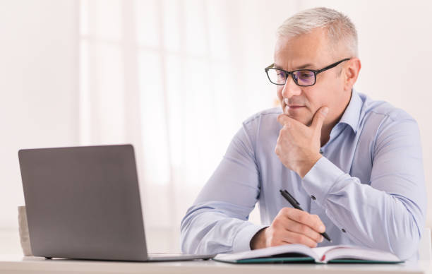 istock Senior man using laptop at home and writing 1210522265