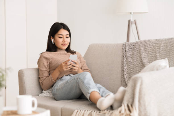 istock Relaxed girl laying on couch and using phone 1210522334