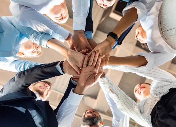 Business Unity And Teambuilding. United Colleagues Standing In Circle Holding Hands Together In Modern Office. Bottom View
