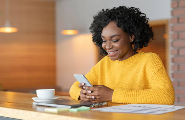 istock Cheerful afro girl chatting at cafe, using smartphone 1210523774