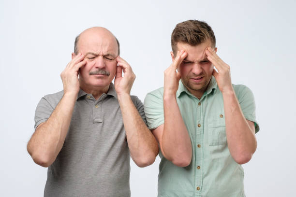 istock Displeased men keep fore fingers on temples, frown faces in discontent, suffer from headache. 1210524167