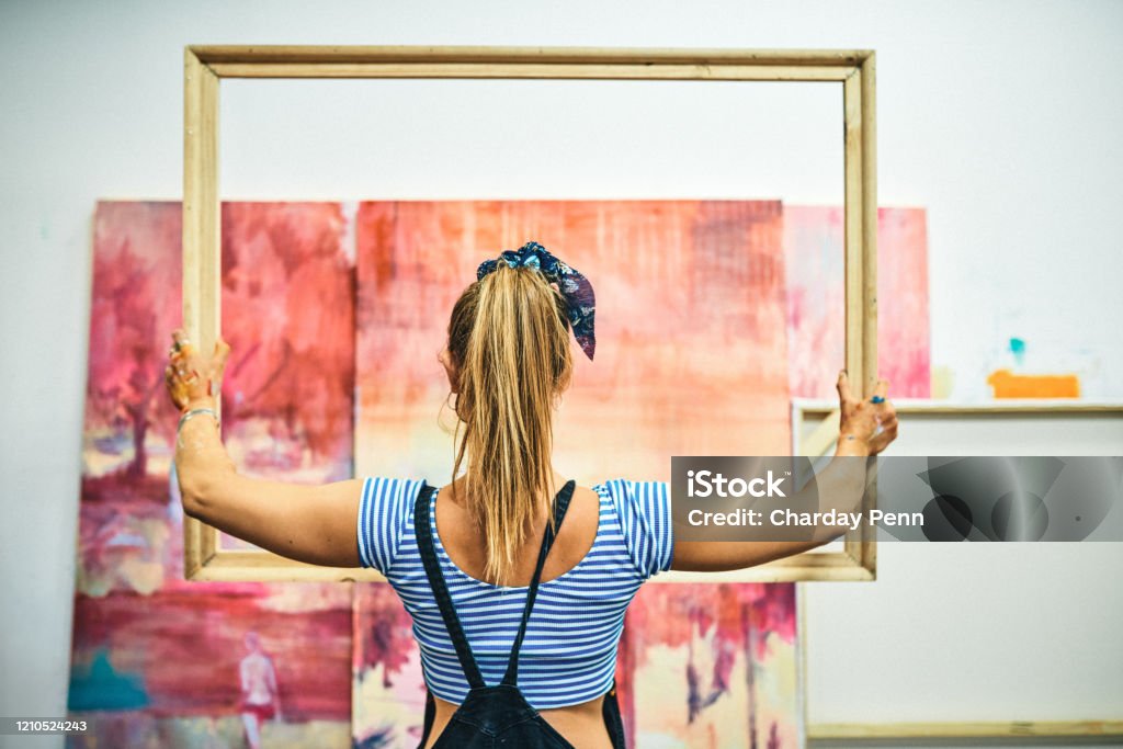 Ready to add the final touch Rearview shot of an unrecognizable woman standing alone and holding a wooden frame in her art studio Artist's Canvas Stock Photo