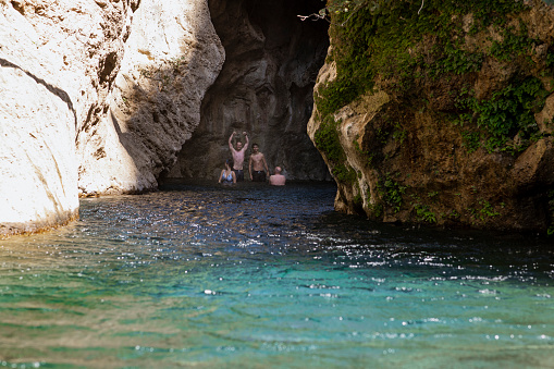 Friends on vacation in Crete swimming in a lake standing in a cave.