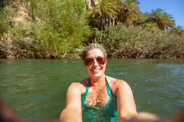 Swimming Selfie Woman taking a selfie while swimming in a lake while on vacation in Crete. river swimming women water stock pictures, royalty-free photos & images