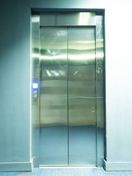 istock View of the metal shiny elevator doors with a burning bright button near it 1210525358