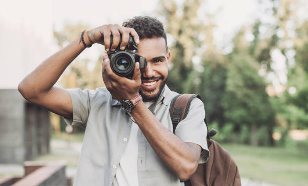 Young man photographer taking pictures in a city Cheerful men photographer with digital camera photographer stock pictures, royalty-free photos & images