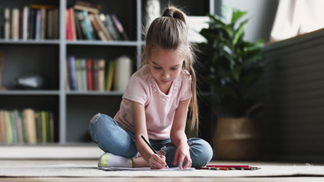 Cute little kid girl drawing colored pencils playing on floor