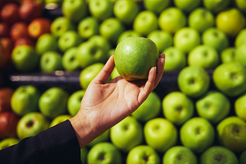 Cropped shot of a woman shopping for apples in a grocery store